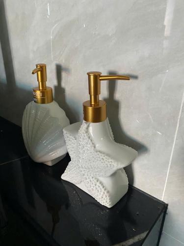two white bottles with gold handles on a black table at Villa Sea in Trà Cổ