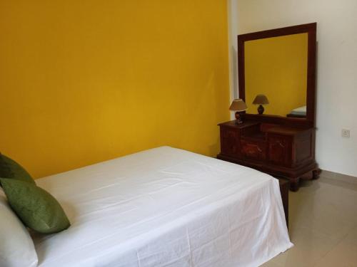 a bedroom with a bed and a dresser and a mirror at Cinnamon Villa Ambalangoda in Ambalangoda