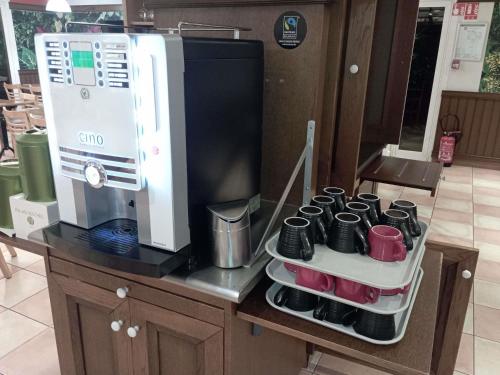 a kitchen counter with a coffee maker and coffee cups at ibis Albert Pays de Somme in Albert