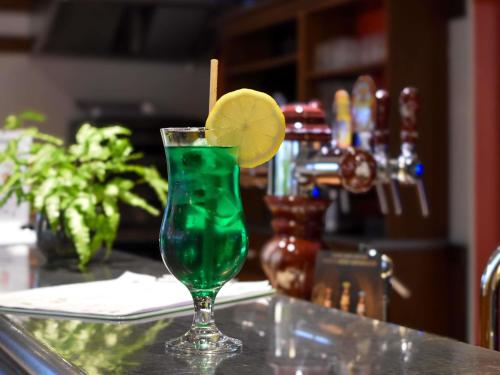 a green drink in a glass with a lemon on a counter at ibis Albert Pays de Somme in Albert