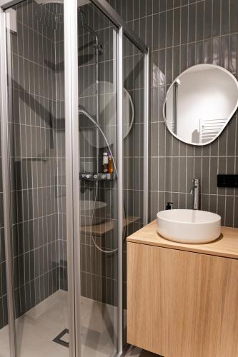 a bathroom with a shower with a sink and a mirror at Design Apartment Bad Aussee in Bad Aussee