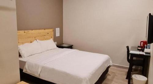 a bedroom with a large white bed and a desk at Sg. Paka Hotel in Paka