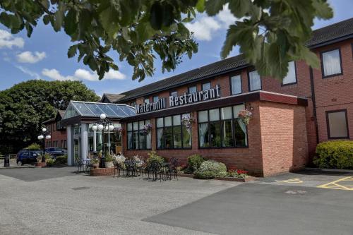 a brick building with tables and chairs in front of it at Best Western Plus Milford Hotel in South Milford