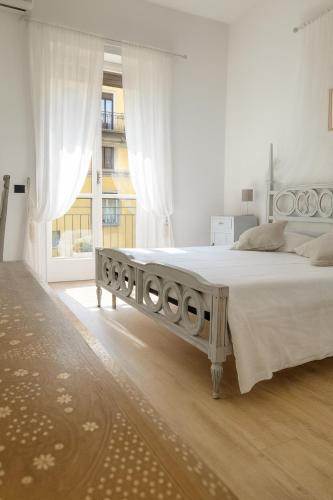 a white bedroom with a large bed with white curtains at Beautiful floral apartment on Navigli in Milan