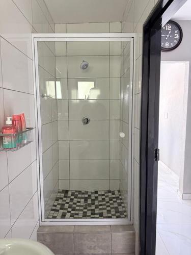 a shower with a glass door in a bathroom at Ella Guest House in Pretoria