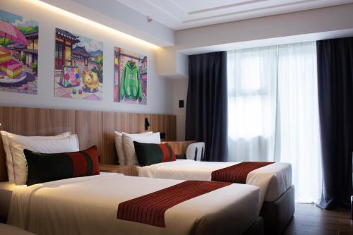 a hotel room with two beds and a window at Novel Hotel Manila in Manila