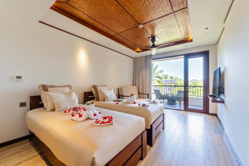 two beds in a room with a tv and a balcony at Hoi An Eco Retreat in Hiếu Nhơn