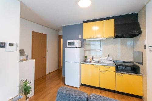 福岡市にあるレトア博多駅南のキッチン(黄色のキャビネット、白い冷蔵庫付)