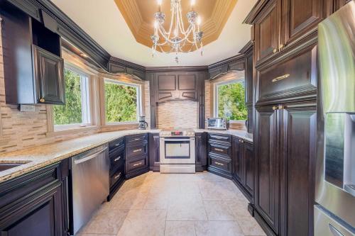 a large kitchen with wooden cabinets and a chandelier at Incredible view - Chateau au bord du fleuve in Saint-Augustin-de-Desmaures