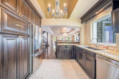 a kitchen with wooden cabinets and a chandelier at Incredible view - Chateau au bord du fleuve in Saint-Augustin-de-Desmaures