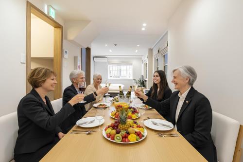 a group of people sitting around a table drinking wine at Hotel STAY ARI Higashishinjuku in Tokyo