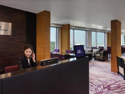 a woman talking on a cell phone in a lobby at Novotel Citygate Hong Kong in Hong Kong