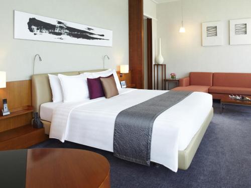a hotel room with a large bed and a couch at Novotel Citygate Hong Kong in Hong Kong