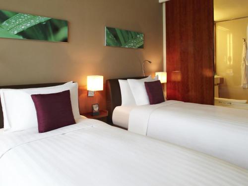 a hotel room with two beds and two lamps at Novotel Citygate Hong Kong in Hong Kong