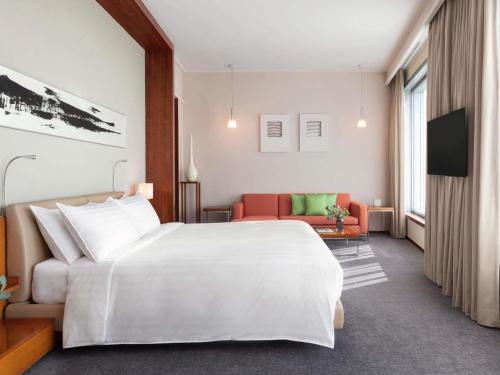 a hotel room with a large white bed and a couch at Novotel Citygate Hong Kong in Hong Kong