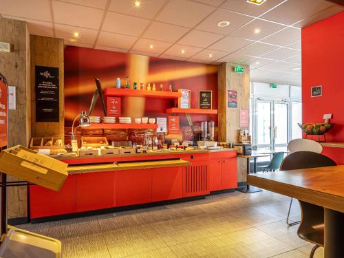 a restaurant kitchen with red cabinets and a counter at ibis Paris Boulogne Billancourt in Boulogne-Billancourt