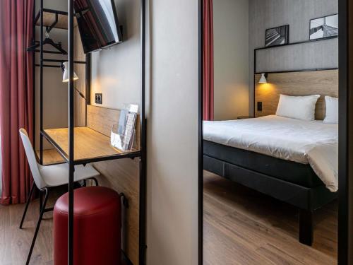 a hotel room with a bed and a desk with a red suitcase at ibis Paris Boulogne Billancourt in Boulogne-Billancourt