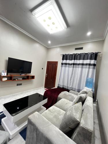 a living room with a couch and a flat screen tv at Hadraj Clocktower Apartment1 in Arusha