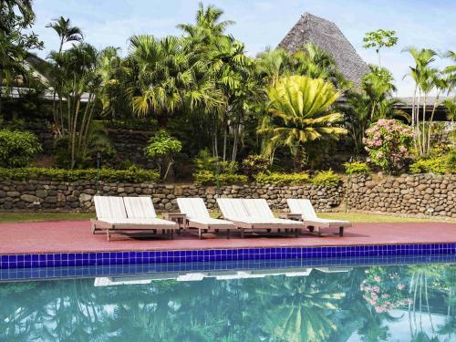 a group of lounge chairs next to a swimming pool at Novotel Nadi in Nadi