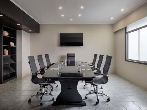 a conference room with a black table and chairs at Novotel Nadi in Nadi