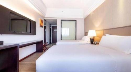a bedroom with a large white bed and a tv at Zhuhai Aqueen Hotel in Zhuhai