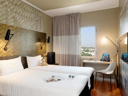 a hotel room with a large white bed and a window at Ibis Casablanca Sidi Maarouf in Casablanca