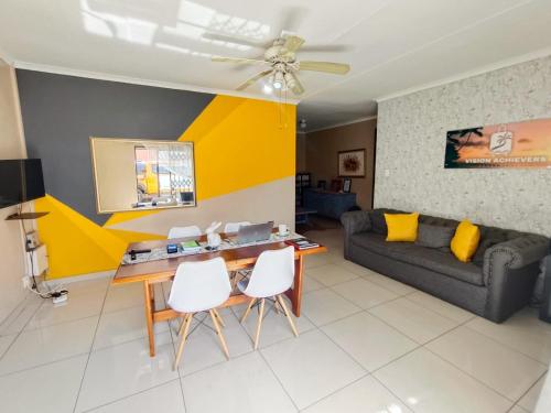a living room with a couch and a table and chairs at Tokelo Guesthouse Emalahleni in Witbank