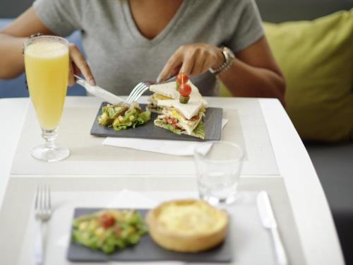a person sitting at a table with a plate of food and a drink at Ibis Casablanca Sidi Maarouf in Casablanca
