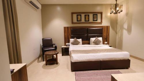 a bedroom with a large bed and a chair at Hotel Imperial Park in Gurgaon