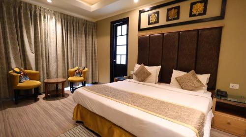 a hotel room with a large bed and two chairs at Hotel Imperial Park in Gurgaon