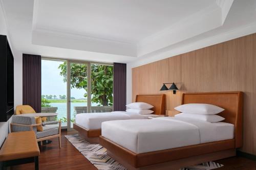 two beds in a bedroom with a view of the water at Sheraton Jakarta Soekarno Hatta Airport in Tangerang