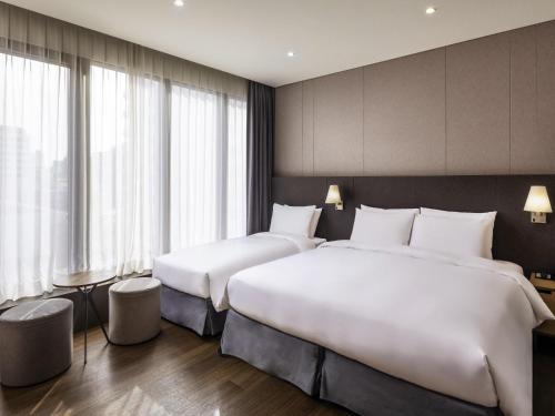 two beds in a hotel room with windows at Ibis Ambassador Myeongdong in Seoul