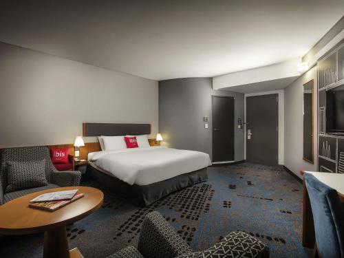 a hotel room with a bed and a table and chairs at Ibis Ambassador Myeongdong in Seoul