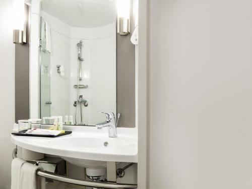a bathroom with a sink and a mirror at Ibis Ambassador Myeongdong in Seoul