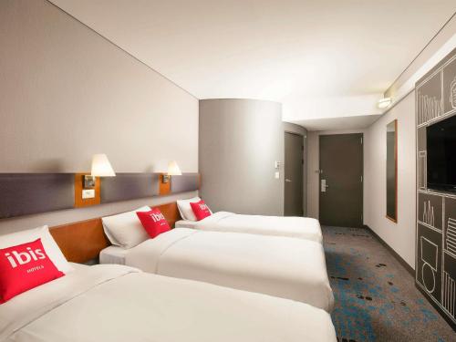 a hotel room with three beds and a flat screen tv at Ibis Ambassador Myeongdong in Seoul