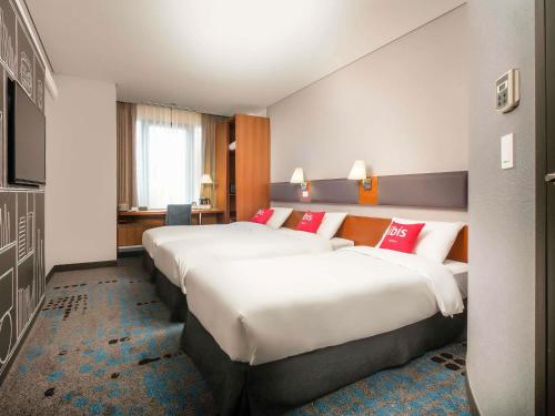 a hotel room with two beds with red pillows at Ibis Ambassador Myeongdong in Seoul