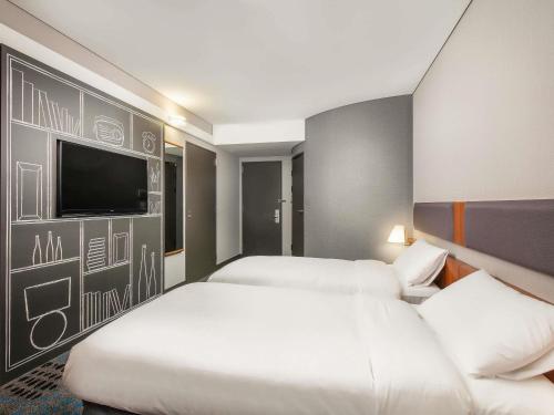 a hotel room with two beds and a flat screen tv at Ibis Ambassador Myeongdong in Seoul