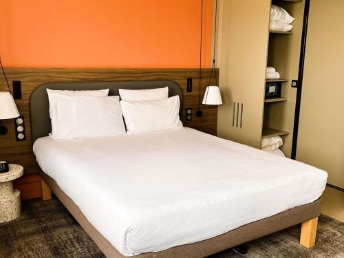 a bed with white sheets and pillows in a room at Novotel Suites Clermont Ferrand Polydome in Clermont-Ferrand