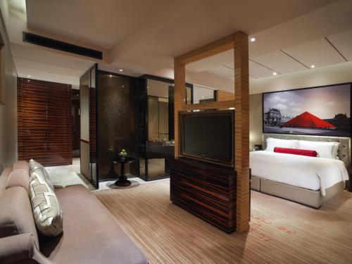 a bedroom with a bed and a flat screen tv at Sofitel Guangzhou Sunrich - Free Shuttle Bus to Canton Fair Complex & Overseas Buyer Registration Services during Canton Fair Period in Guangzhou