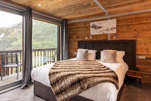 Un dormitorio con una cama y una ventana grande. en Black Diamond - Chalet Charlie, en Les Brévières
