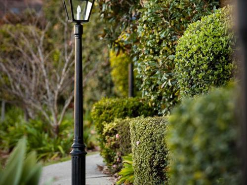 a black lamp post in a garden with bushes at Peppers The Hills Lodge in Castle Hill