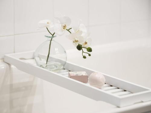 a white shelf with a vase with flowers in it at Peppers The Hills Lodge in Castle Hill