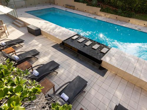 an overhead view of a swimming pool with chairs and tables at Peppers The Hills Lodge in Castle Hill