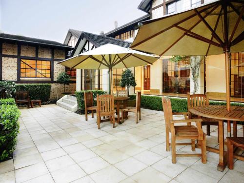 a patio with tables and chairs and umbrellas at Peppers The Hills Lodge in Castle Hill