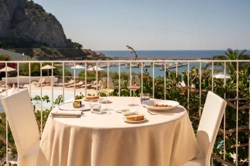 a table with wine glasses and food on it with the beach at Le Calette N.5 in Cefalù