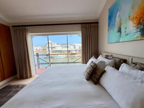 a bedroom with a large white bed with a large window at Spinnaker Quays Waterfront Villa in Knysna