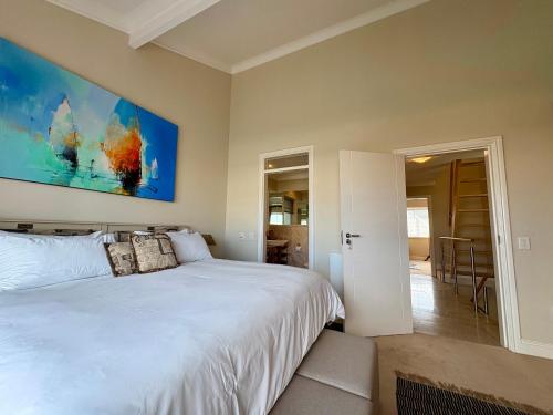 a bedroom with a white bed and a painting on the wall at Spinnaker Quays Waterfront Villa in Knysna