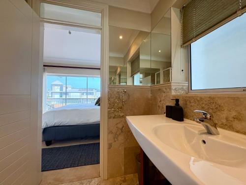 a bathroom with a sink and a mirror and a bed at Spinnaker Quays Waterfront Villa in Knysna