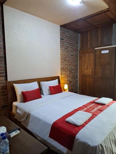 a bedroom with a large bed with red and white pillows at Balkondes Tuksongo in Borobudur