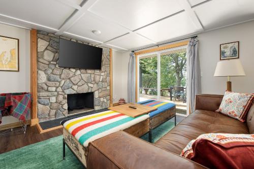 a living room with a couch and a stone fireplace at Dyer Lake Gallery Retreat - Lakefront - Deck - Fire Pit in Grawn